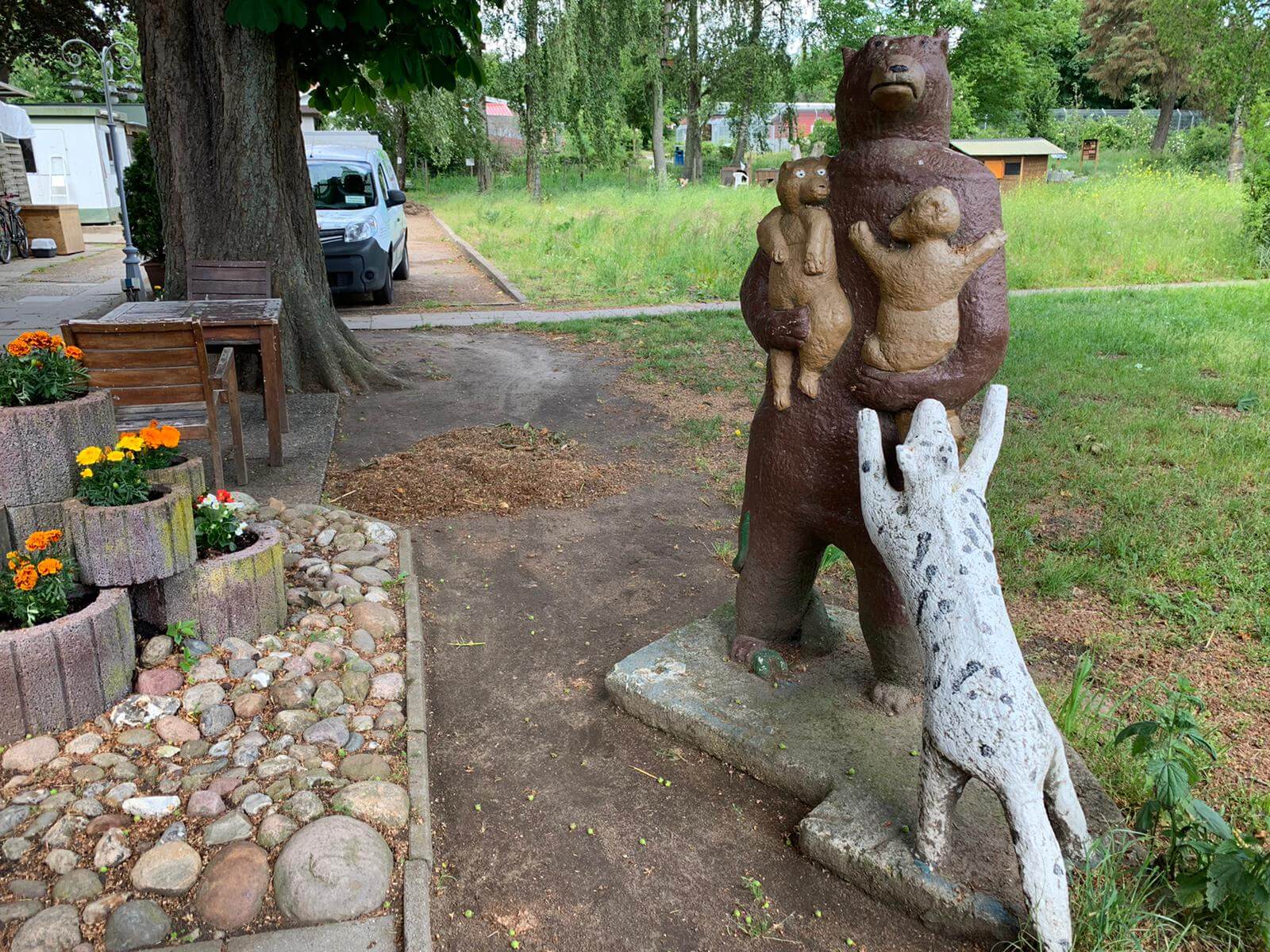 Ein Bär, der seinen Jungen in den Armen hält und ein Hund als Steinfigur